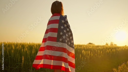 Silhouette girl holding American stars and stripes flag, standing in summer sunshine photo
