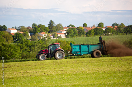 Tracteur pratiquant de l'épandage en campagne devant un village en France. photo