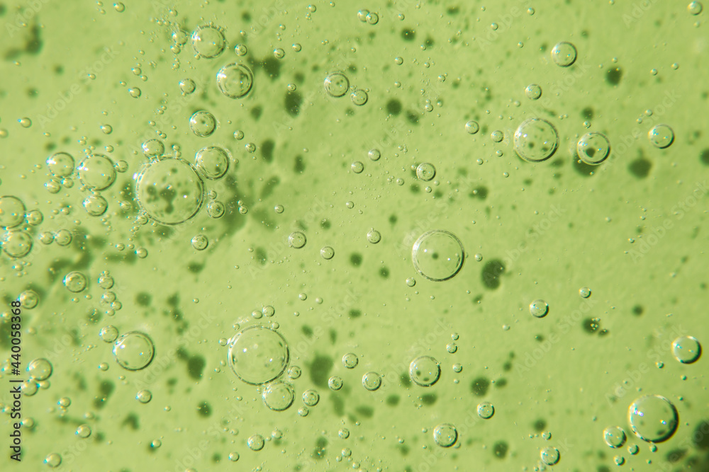 Cosmetic texture with bubbles on pastel green background. Cleanser, shampoo, wash - liquid soap, shower gel, hyaluronic acid, serum. Cosmetics banner