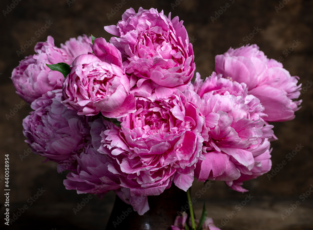 Beautiful bouquet of pink peonies in vase on a wooden table