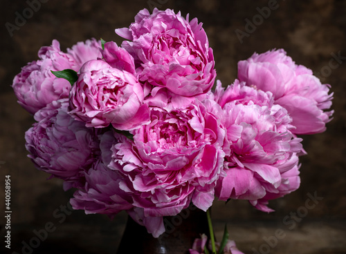 Beautiful bouquet of pink peonies in vase on a wooden table