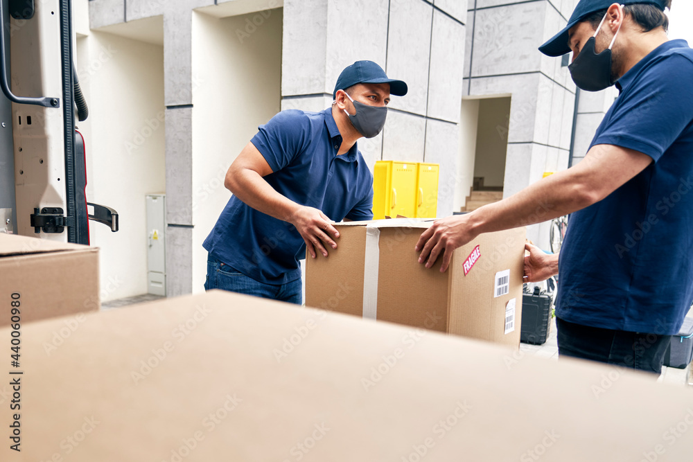 Couriers unloading packages from a delivery truck during a pandemic Couriers unloading packages from a delivery truck during a pandemic