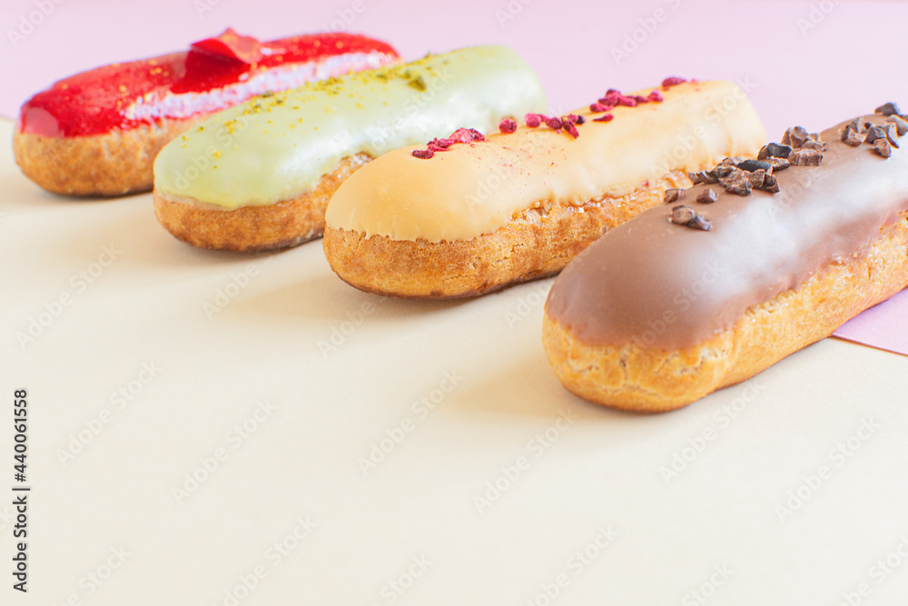 Eclairs on a minimal background. Still life hello dessert mood. Traditional French dessert with colorful icing. Concept baking, cookbook recipes, bakery banner, cafe advertisement. Eclairs on a minimal background. Still life hello dessert mood. Traditional French dessert with colorful icing. Concept baking, cookbook recipes, bakery banner, cafe advertisement.