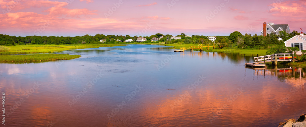 Sunset seascape with pink clouds and water reflections. Peaceful summer marsh river landscape over Bumps River near Craigville Beach on Cape Cod.  