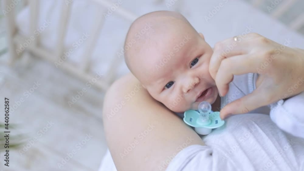 mom cradles and calms the capricious baby in her arms with a pacifier, the newborn falls asleep mom cradles and calms the capricious baby in her arms with a pacifier, the newborn falls asleep