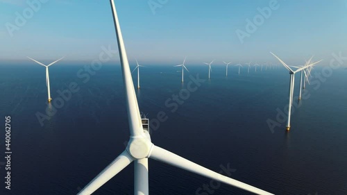 offshore windmill park with clouds and a blue sky, windmill park in the ocean aerial view with wind turbine Flevoland Netherlands Ijsselmeer. Green energy  photo