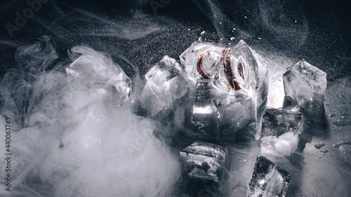 Rings frozen in ice with water and smoke on black background (ID: 440063769)