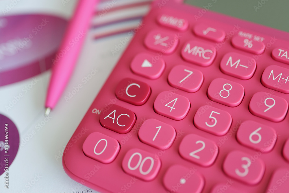 Pink calculator lying on documents with graphs near ballpoint pen closeup Pink calculator lying on documents with graphs near ballpoint pen closeup