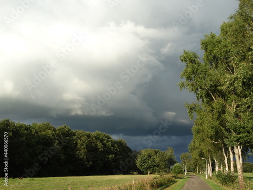 Thunder clouds. Dramatic dark sky in green summer landscape. Panoramic view on thunderstorm. Background. Onweerswolk. Code geel. Code oranje. Dreigende wolk boven groen zomer landschap. photo