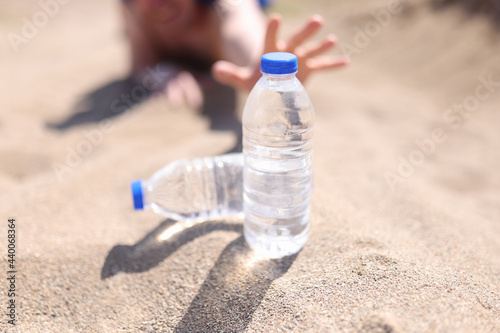 Male hands reaching for plastic water bottle in desert closeup