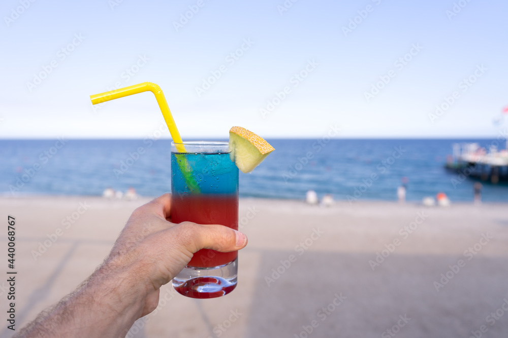 Colorful blue and red layered tropical alcohol coctails with straws on the background of Warm Blue Sea. Exotic Summer Vacation. Colorful blue and red layered tropical alcohol coctails with straws on the background of Warm Blue Sea. Exotic Summer Vacation.