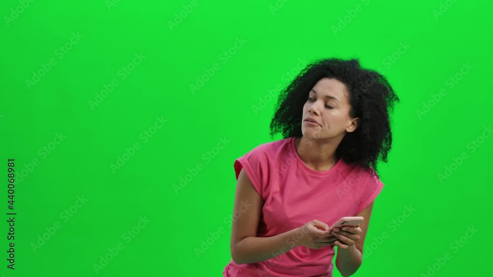 Portrait of young female African American viewing the map on a smartphone to get to the right place. Black woman with curly hair poses on green screen in studio. Close up. Slow motion ready 59.97fps. Portrait of young female African American viewing the map on a smartphone to get to the right place. Black woman with curly hair poses on green screen in studio. Close up. Slow motion ready 59.97fps.
