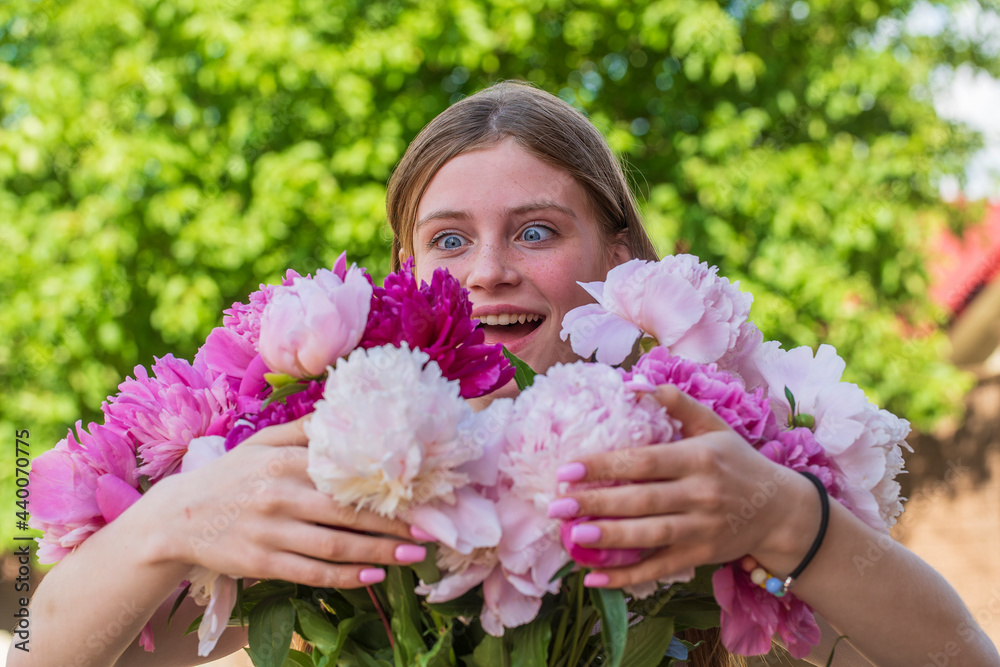 Beautiful and happy young girl in the summer with a beautiful bouquet of peonies in nature Beautiful and happy young girl in the summer with a beautiful bouquet of peonies in nature
