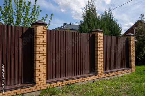 Fence or fence of brown metal and brick columns. The concept of safety,