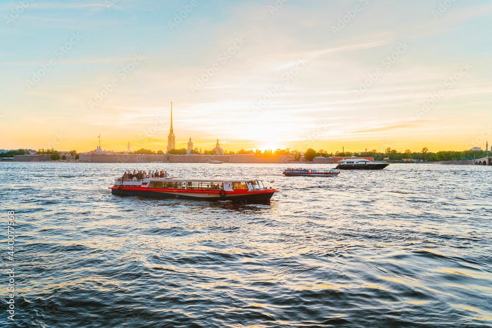 Panoramic view of the beautiful sunset over the Neva River in St. Petersburg and pleasure boats with tourists. Saint Petersburg, Russia - 05 Apr 2021 Panoramic view of the beautiful sunset over the Neva River in St. Petersburg and pleasure boats with tourists. Saint Petersburg, Russia - 05 Apr 2021
