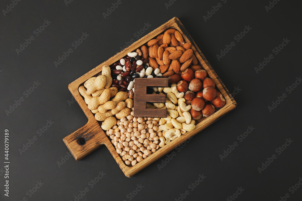 Board with different healthy nuts and beans rich in vitamin E on dark background Board with different healthy nuts and beans rich in vitamin E on dark background