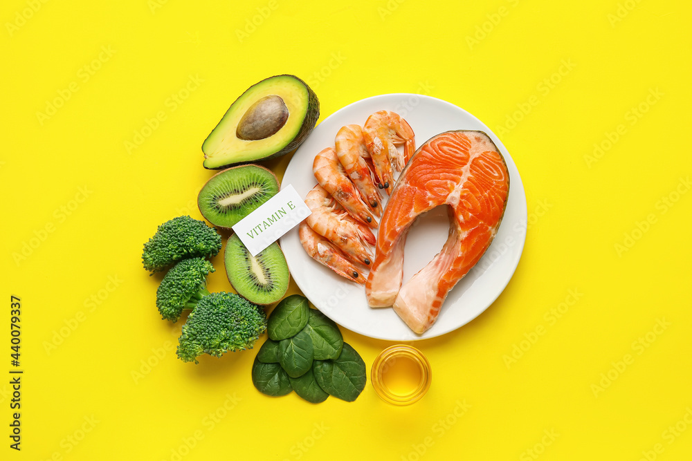 Plate with healthy products rich in vitamin E on color background