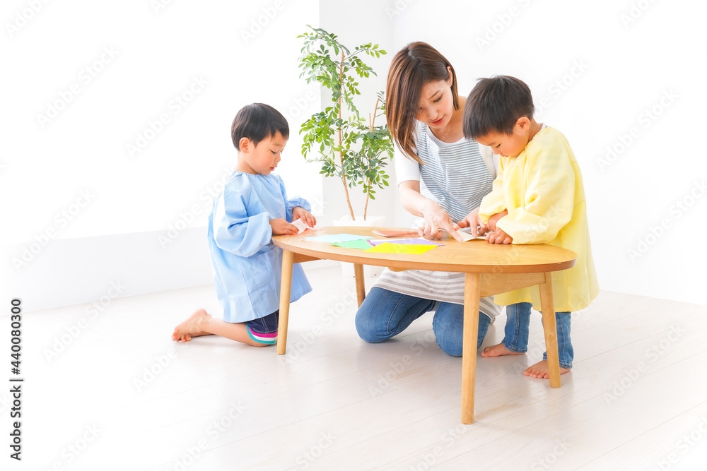 幼稚園で折り紙をする子どもと先生