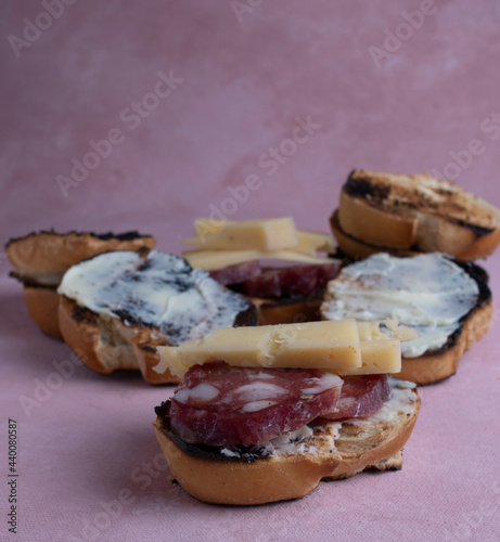 Salami and cheese with toast on a textured background. It is a concept of fast food made at home. Homemade cold cuts with delicious country toasts.

 photo