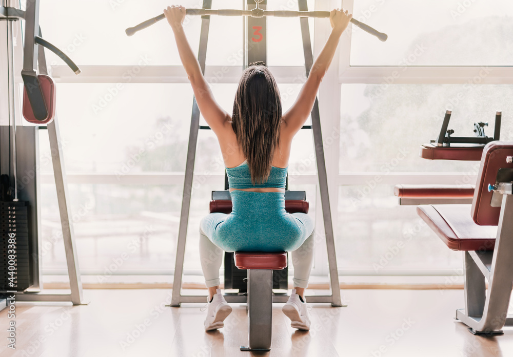 girl practicing strength exercise with a rowing machine. horizontal format. backlight with large window. natural light. girl practicing strength exercise with a rowing machine. horizontal format. backlight with large window. natural light.