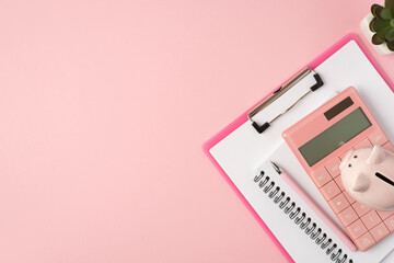 Top view photo of piggybank on pink calculator clipboard planner pen and plant on isolated pastel pink background with copyspace
