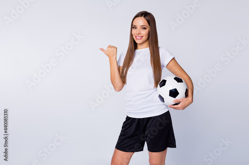 Photo of attractive lady direct thumb finger side empty space advising watch soccer match banner hold leather ball wear football uniform t-shirt shorts isolated white color background