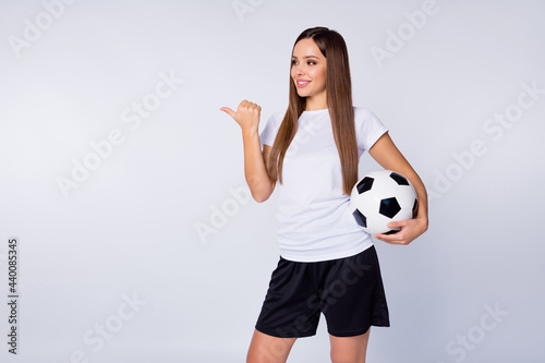 Photo of funny lady direct finger side empty space advising watch soccer match sports bar pub hold leather ball wear football uniform t-shirt shorts isolated white color background © deagreez