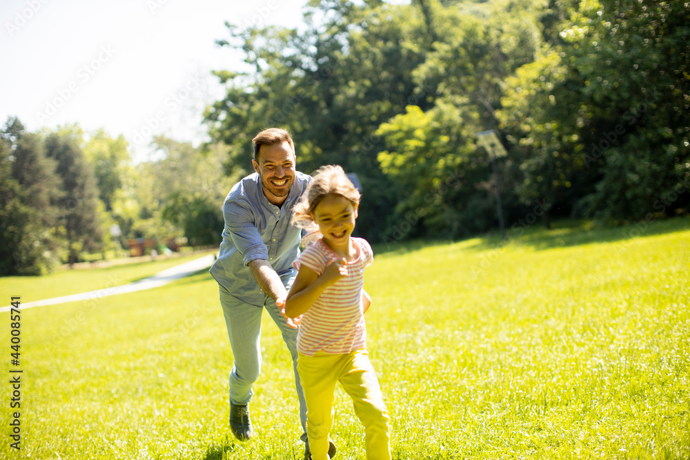 Fototapeta premium Father chasing his little daughter while playing in the park