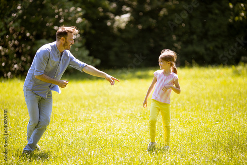 Fototapeta Father chasing his little daughter while playing in the park