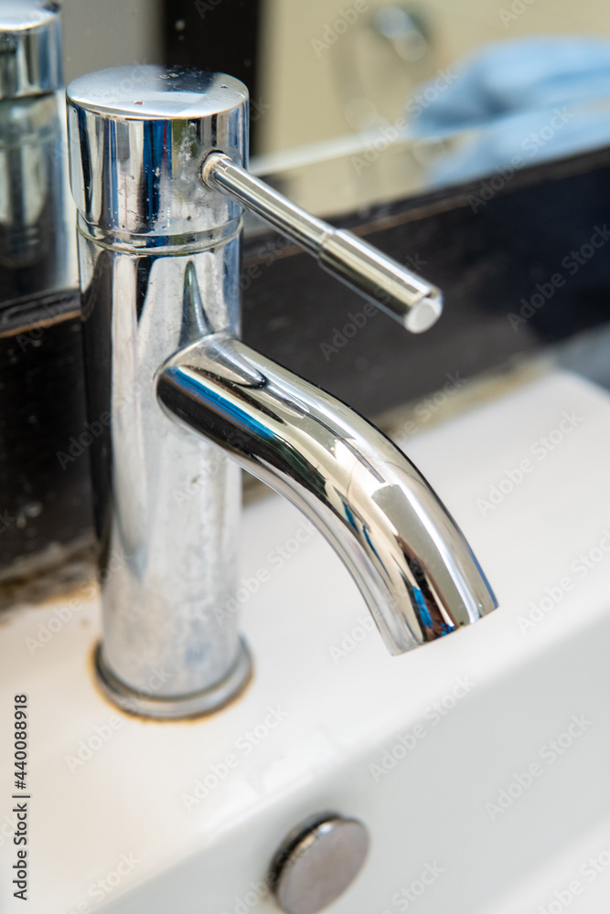 Clear water is running from shiny faucel into the sink in bathroom, closeup view. Water system in residental real estate concept. Clear water is running from shiny faucel into the sink in bathroom, closeup view. Water system in residental real estate concept.