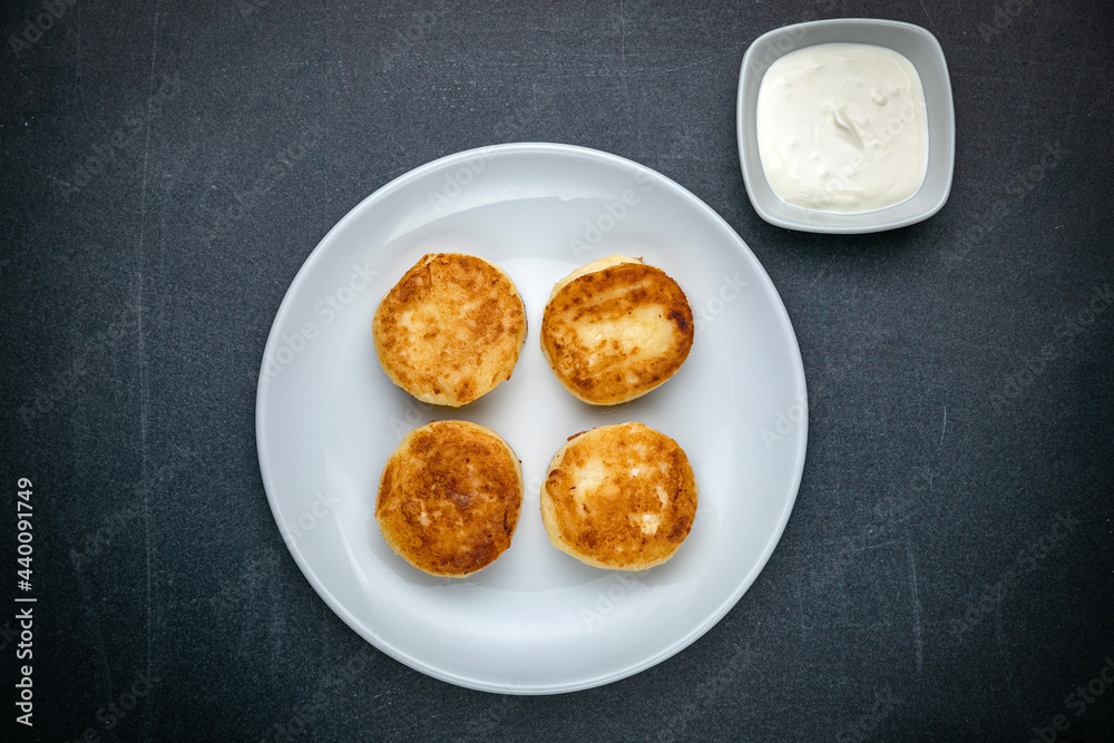 Cheesecakes on a dark table with sour cream
Cheesecakes on a dark table with sour cream