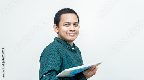 Portrait of an Asian Malay man with green casual shirt holding files. Lets study and learn concept. Come and join us.