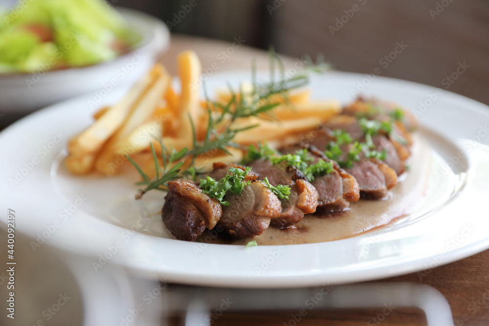 Duck magret confit with chips on wood table Duck magret confit with chips on wood table