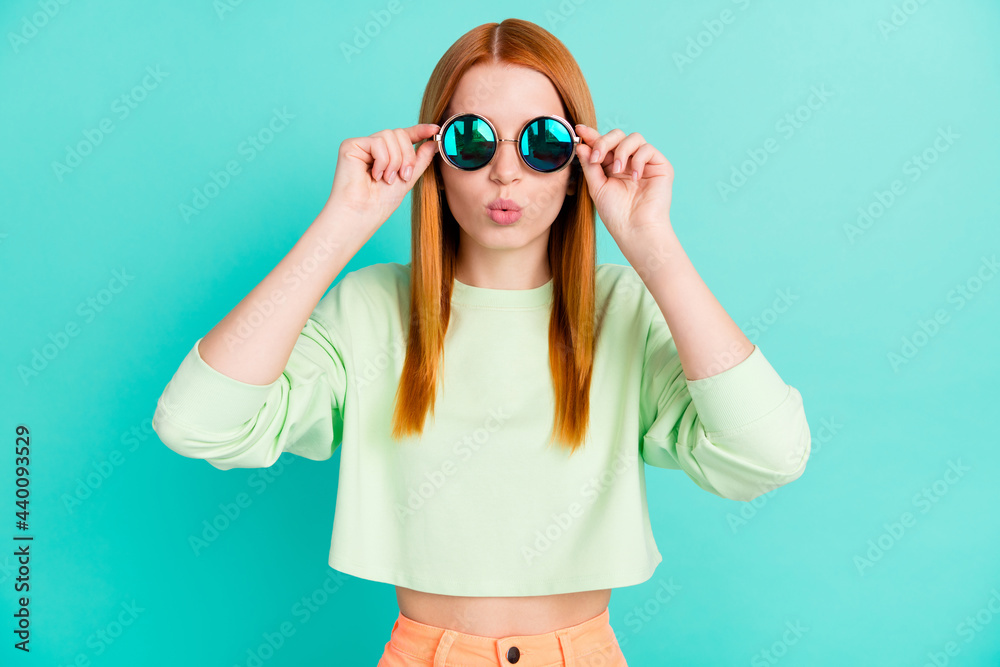 Photo of shiny impressed young woman wear green shirt arms dark glasses lips pouted isolated teal color background Photo of shiny impressed young woman wear green shirt arms dark glasses lips pouted isolated teal color background