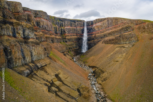 Aerial view of Hengifoss waterfall in East Iceland. Hengifoss is the third highest waterfall in Iceland and is surrounded by basaltic strata with red layers of clay between the basaltic layers.