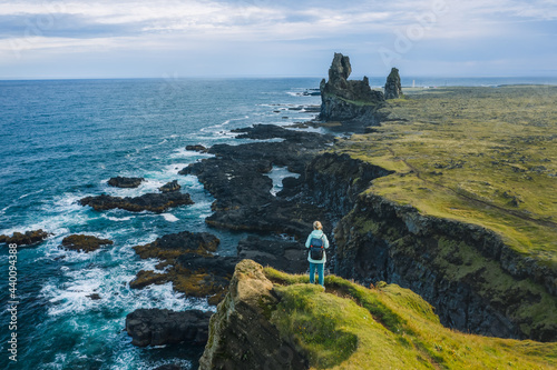 Man hiker in yellow jacket stand on the peak of the rock in outdoor park in Iceland. Londrangar photo
