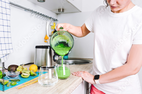 A woman is preparing a homemade detox juice or concentrated vitamin smoothie in blender. Healthy lifestyle, healthy sports nutrition.
