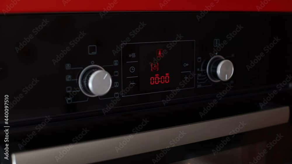 Woman hand push security key button from kids on the electric oven console Woman hand push security key button from kids on the electric oven console