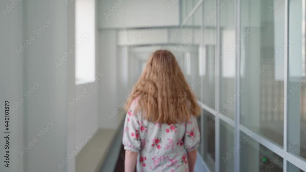Unrecognizable girl walk along corridor until out of focus indoors. Young adult woman in office place walking Unrecognizable girl walk along corridor until out of focus indoors. Young adult woman in office place walking