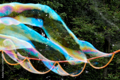 the process of blowing soap bubbles in the park against the background of trees