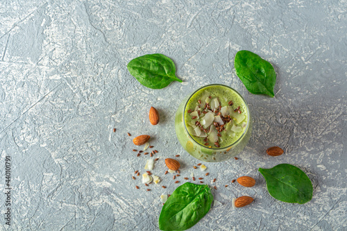Glass with green smoothie from spinach, avocado, celery, kiwi and coconut milk, served with coconut flakes, flaxseed and almonds. Home cooking. Vegan healthy detox eating, dietary 