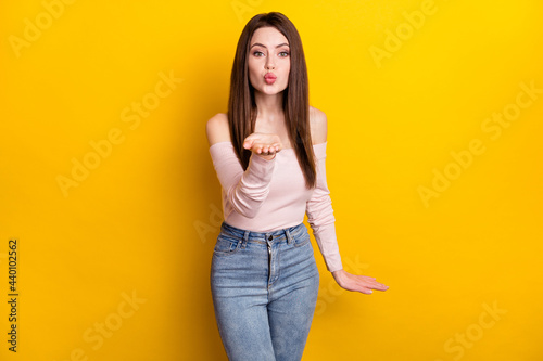 Photo of optimistic brunette lady blow kiss wear pink shirt isolated on yellow color background