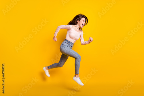 Full size profile side photo of young happy excited girl look copyspace running in air isolated on yellow color background
