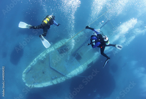 Bild auf Leinwand Scuba Divers go down the rope and Exploring underwater ship wreck