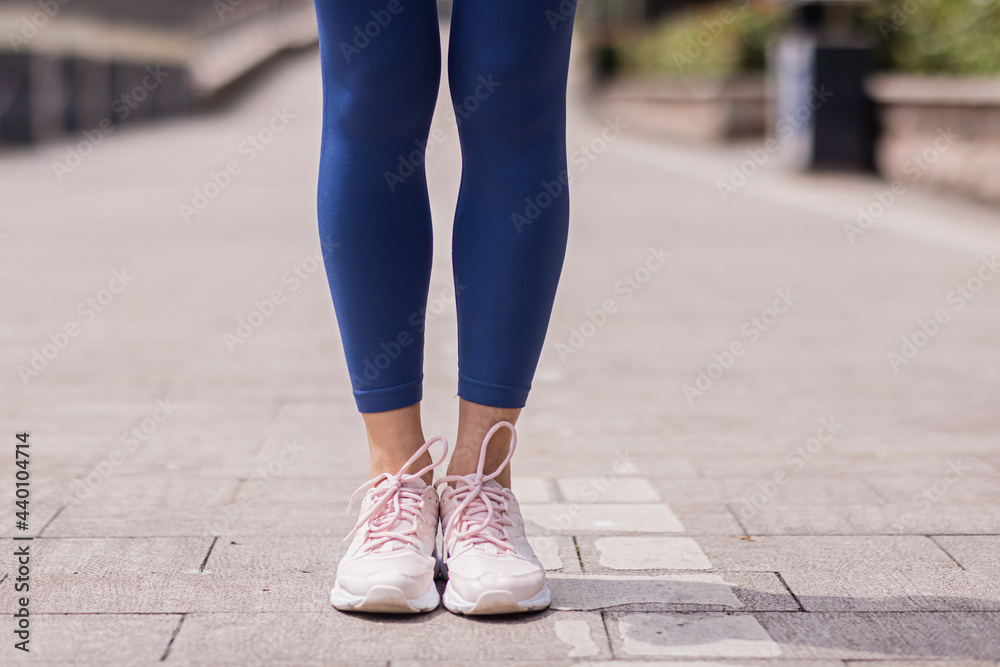 Young brunette Woman running on asphalt road in summer park. Active sporty caucasian female has morning workout. Athletic person in sportswear exercises outdoor. Dressed leggings and sportive top