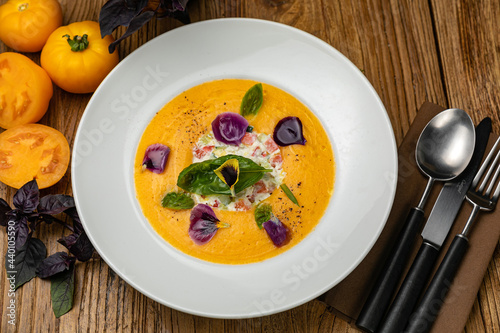 Tomato puree soup with yellow tomatoes on a wooden table
