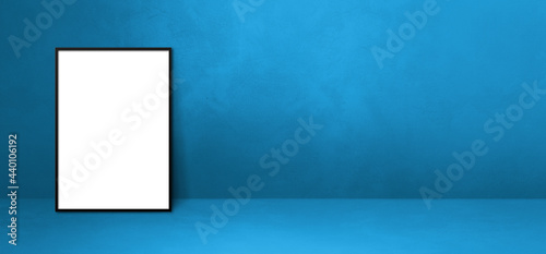 Black picture frame leaning on a blue wall. Horizontal banner