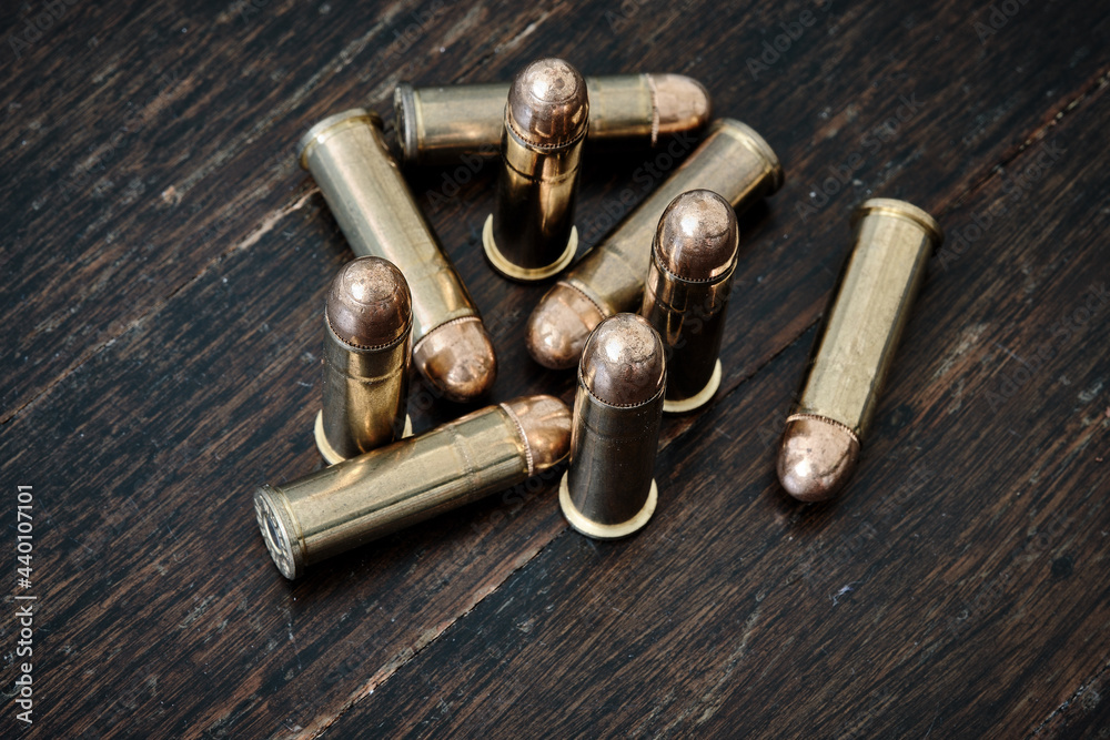 Brass handgun ammunition against a wooden backdrop