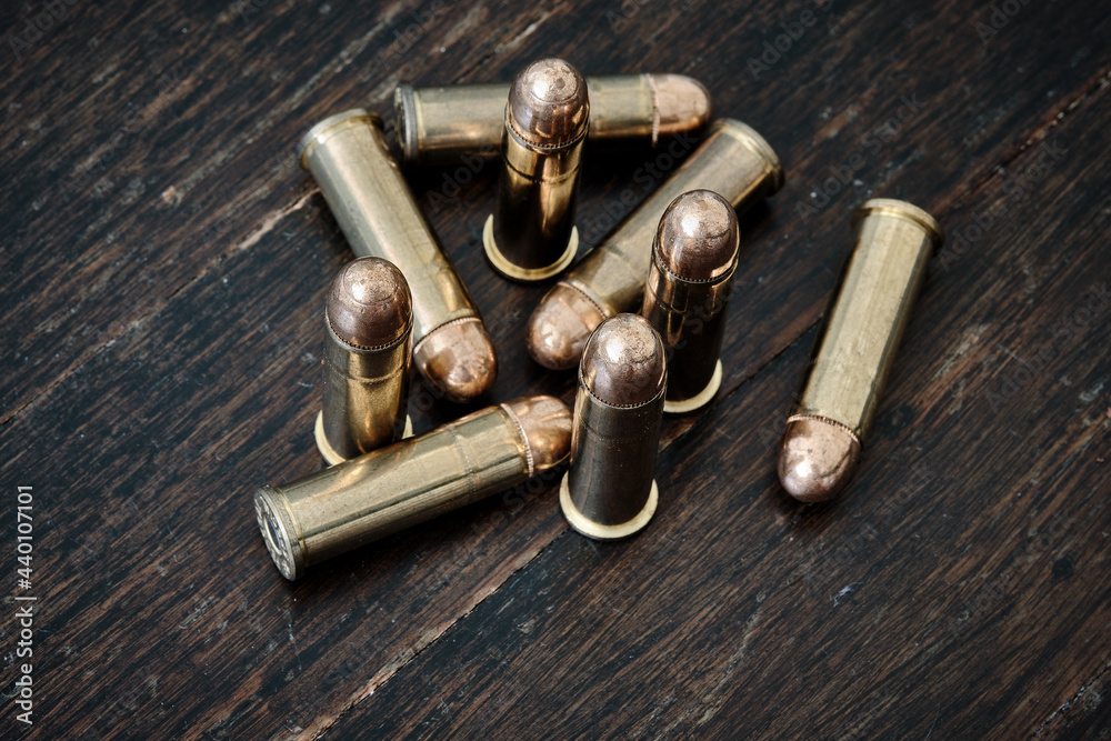 Brass handgun ammunition against a wooden backdrop Brass handgun ammunition against a wooden backdrop