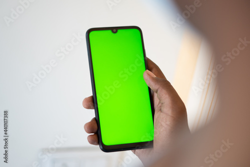 Closeup shot of hand using mobile phone with Green screen, Finger swiping up and down in green screen of the mobile. Green screen mockup template of Mobile phone, Chroma key	